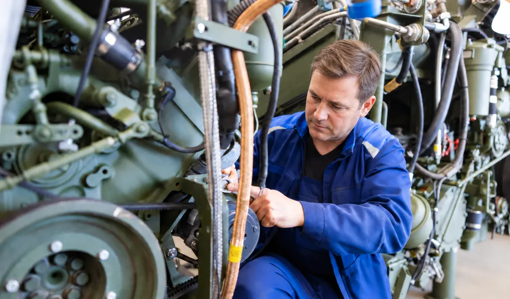 Kfz-Mechaniker montiert Bauteile an einem Fahrzeugmotor in der Werkstatt