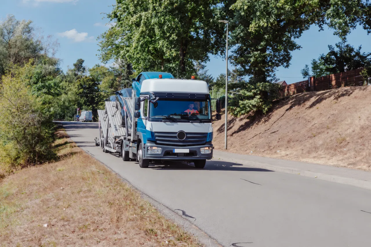 Autotransporter mit Fahrer fährt eine Landstraße entlang