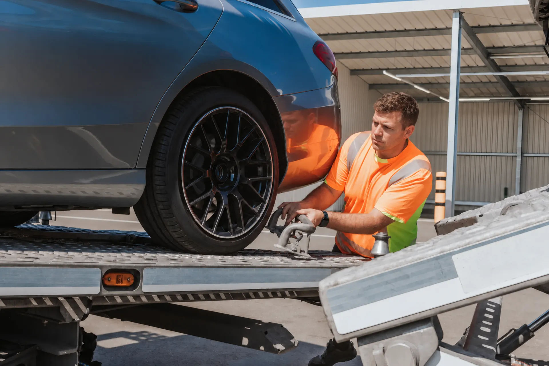 Fahrer sichert ein Auto auf der Ladefläche seines Transporters